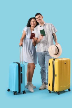 Mavi arka planda bavulları ve pasaportları olan iki turist.
