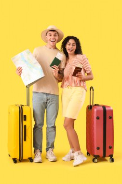 Sarı arka planda bavulları ve pasaportları olan iki turist.