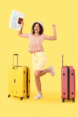 Sarı arka planda haritası ve bavulları olan neşeli Afro-Amerikan bayan turist.