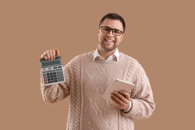 Kahverengi arka planda hesap makinesi ve tablet bilgisayarı olan bir erkek muhasebeci.