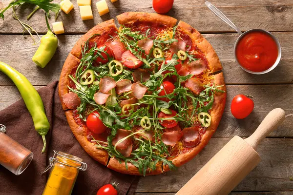 Domatesli lezzetli pizza ve ahşap arka planda roka.