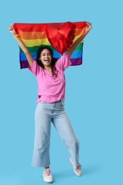 Gökkuşağı bayrağı ve mavi arka planda kalp şeklinde balonu olan mutlu Afro-Amerikalı kadın. LGBT kavramı