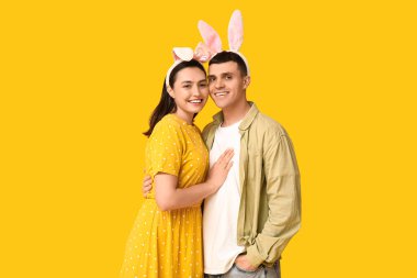Sarı arka planda Paskalya tavşanı kulakları olan mutlu genç çift.