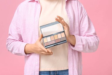 Pembe arka planda göz falı olan bir kadın.