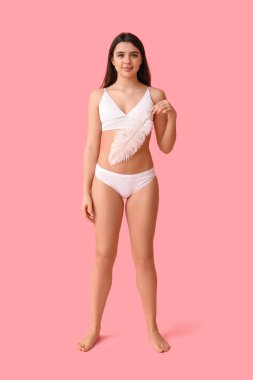 Pembe arka planda yumuşak tüyleri olan güzel genç bir kadın. Epilasyon kavramı