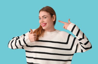 Güzel genç bayan mavi arka planda işitme cihazına işaret ediyor.