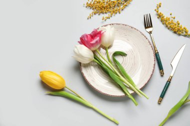 Gri arkaplanda güzel laleler ve mimoza çiçekleri olan masa ayarı