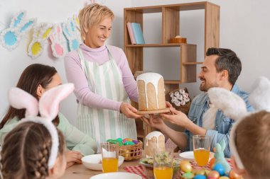 Olgun bir kadın ailesiyle akşam yemeği için Paskalya pastası getiriyor.