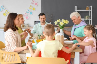 Büyük bir aile mutfakta Paskalya yemeğinden önce dua ediyor.