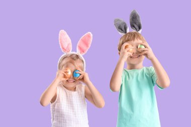 Paskalya yumurtaları ve leylak arka planda tavşan kulaklı küçük çocuklar.