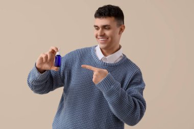 Genç adam arka planda bir şişe CBD yağını işaret ediyor.
