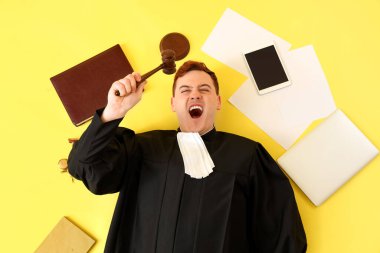 Male judge with gavel and items on yellow background, top view clipart