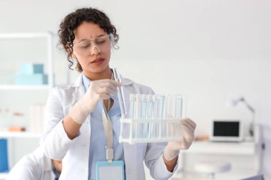 Laboratuvarda test tüpleri olan Afro-Amerikalı bir kimyager.