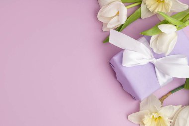 Güzel laleli hediye kutusu ve leylak arkaplanlı nergis çiçekleri.