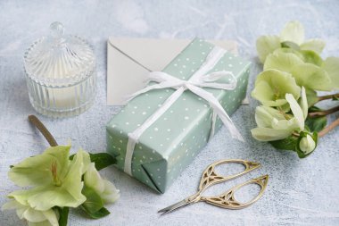 İçinde güzel çiçekler, zarf ve arkaplanda mum olan hediye kutusu.