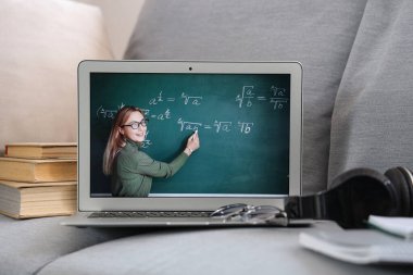 Matematik öğretmeninin odada kanepede online ders verdiği dizüstü bilgisayar ekranı.