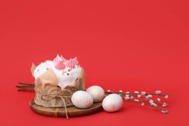 Paskalya pastası, ahşap tepside boyanmış yumurtalar ve kırmızı arka planda söğüt dalları.