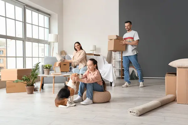 Happy family with Beagle dog packing things in room on moving day