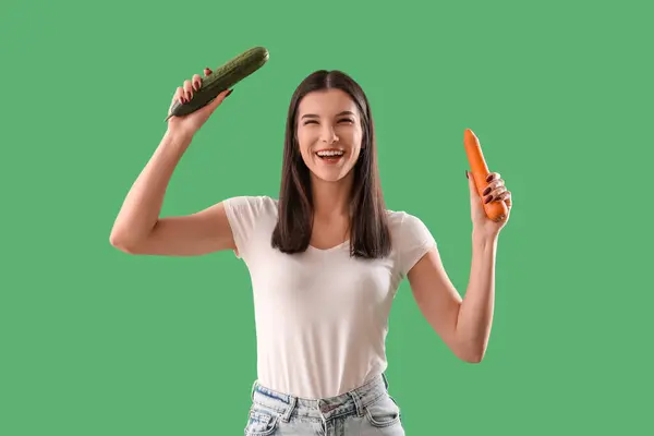 緑色の背景にニンジンとキュウリを持つ若い女性 ダイエットコンセプト — ストック写真