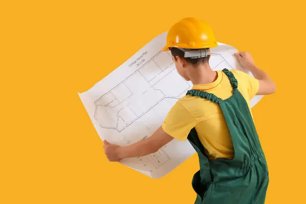 Little architect with house plan on yellow background, back view