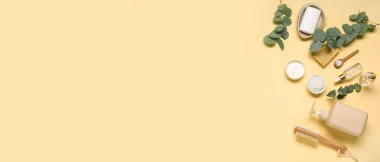 Bej arka planda farklı kozmetik ürünleri ve okaliptüs dalları ile metin ve üst görünüm için alanı olan kompozisyon