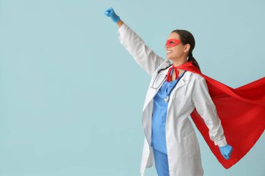 Mavi arka planda süper kahraman gibi giyinmiş güzel bir kadın doktor.