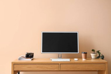 Modern bilgisayarlı şık bir iş yeri ve renkli duvarın yanında bir fincan kahve.