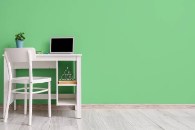 Yeşil duvarın yanında modern dizüstü bilgisayarı olan şık bir iş yeri