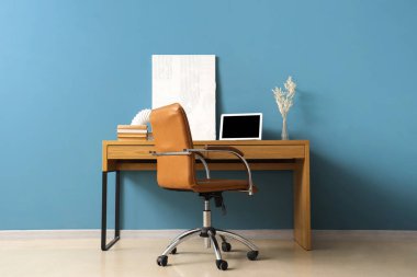 Modern dizüstü bilgisayarı ve renkli duvarın yanındaki rahat koltuğu olan şık bir iş yeri.