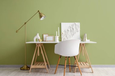 Mumları olan şık bir iş yeri, boş resim çerçeveleri ve renk duvarının yanındaki dekor