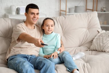 Mutlu baba ve küçük kızı evdeki kanepede televizyon izliyorlar.