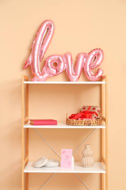 İçinde balonlardan ve bej duvarın yanındaki hediye kutularından yapılmış aşk sözcüğü olan kitaplık. Sevgililer Günü kutlaması
