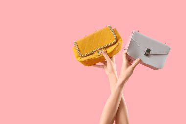 Pembe arka planda farklı tarz kadın çantaları olan kadın elleri.