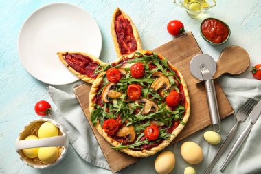 Lezzetli pizzayla kompozisyon ve mavi arka planda Paskalya kutlaması için boyanmış yumurta.