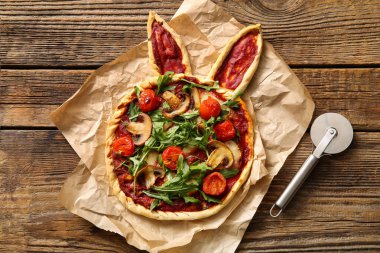 Tahta arka planda lezzetli pizza ve kesici. Paskalya kutlaması