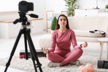 Kadın spor blogcusu evde video kaydederken meditasyon yapıyor