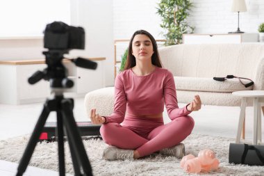 Kadın spor blogcusu evde video kaydederken meditasyon yapıyor