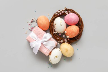 Boyanmış Paskalya yumurtaları ve gri arka planda hediye kutusu.