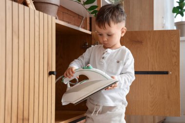 Evdeki çekmeceden elektrikli ütü alan küçük çocuk. Çocuk tehlikede.