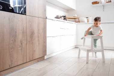 Küçük çocuk mutfakta merdivene tırmanıyor. Tehlikedeki çocuk