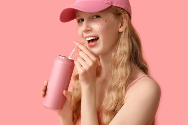 Pembe arka planda bir kutu gazozu olan güzel genç bir kadın.