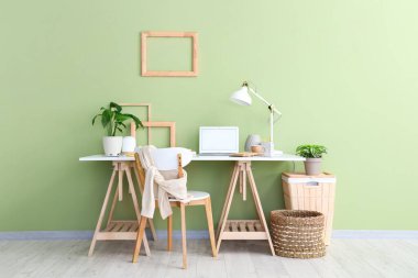 Işık ofisinde lamba, ev bitkisi ve dizüstü bilgisayarı olan işyeri