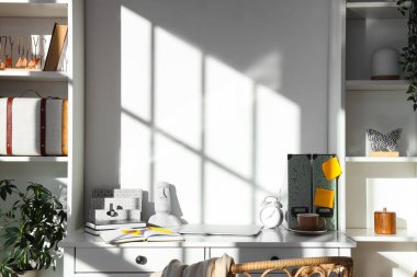 Ofisinde defter, dizüstü bilgisayar ve bir fincan kahve olan modern bir iş yeri.