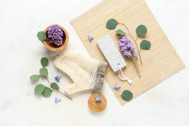 Hafif arkaplanda spa malzemeleri, çiçekler ve okaliptüs dallarıyla kompozisyon