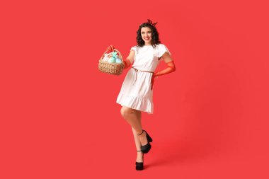 Kırmızı arka planda Paskalya sepeti tutan güzel bir kadın.