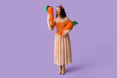 Leylak arka planında oyuncak havuç tutan güzel bir kadın.