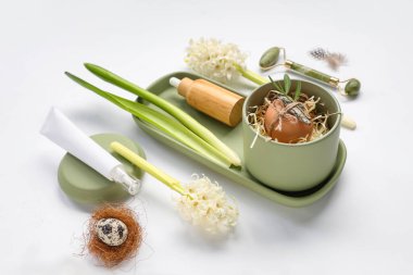 Işık arka planında kaplıca aksesuarları, çiçekler ve Paskalya dekoru olan güzel bir kompozisyon