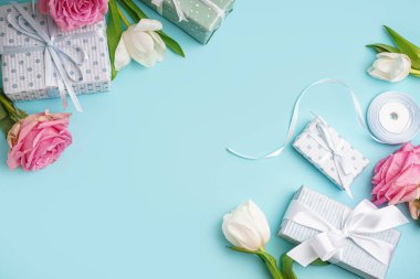 Güzel laleli hediye kutuları ve mavi arka planda pembe güller.