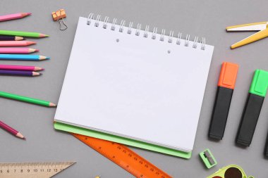 Gri arka planda kalem ve makaslı defter. Üst görünüm