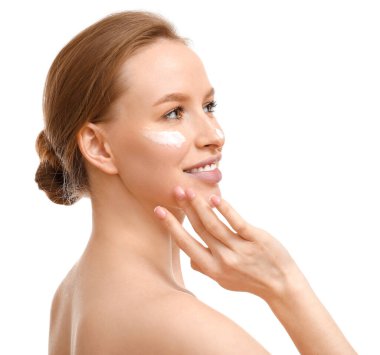 Genç bir kadın beyaz arka plana krem sürüyor.